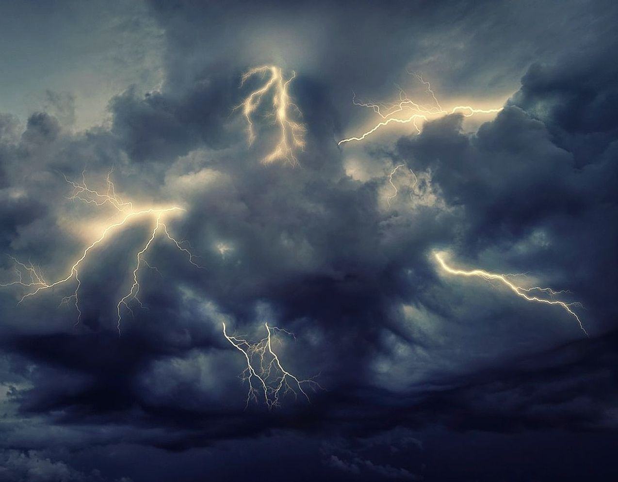 A workspace with storm photographs, contact sheets, and field notes from lightning captures